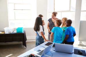 A teacher talking with a group of students in a classroom