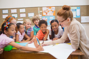 teacher and pupils working at desk together at the elementary