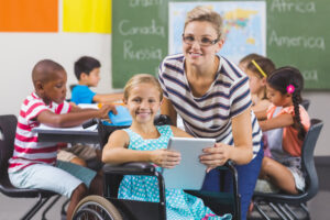 smiling schoolgirl and teacher using digital tablet in classroom at school