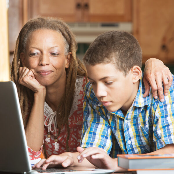 mother,overlooks,as,her,teenaged,son,uses,his,laptop,to