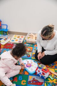 A teacher and a young child working together on a play mat