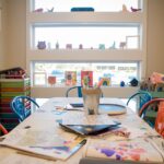 A table in a children's classroom, covered in drawings and crayons