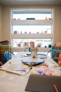 A table in a children's classroom, covered in drawings and crayons