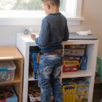 A child standing by a window, in front of a set of cubbies