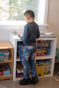 A child standing by a window, in front of a set of cubbies