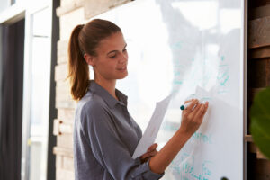 smiling,woman,in,an,office,writing,on,a,whiteboard,,close